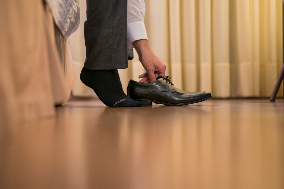 Making of no salão Camaleão cabelo e estética, do casamento lindo da Ana Maria e Ricardo, fotografado pelo fotógrafo de casamentos em Campo Largo e Curitiba, Michel Druziki. Noivo colocando os sapatos