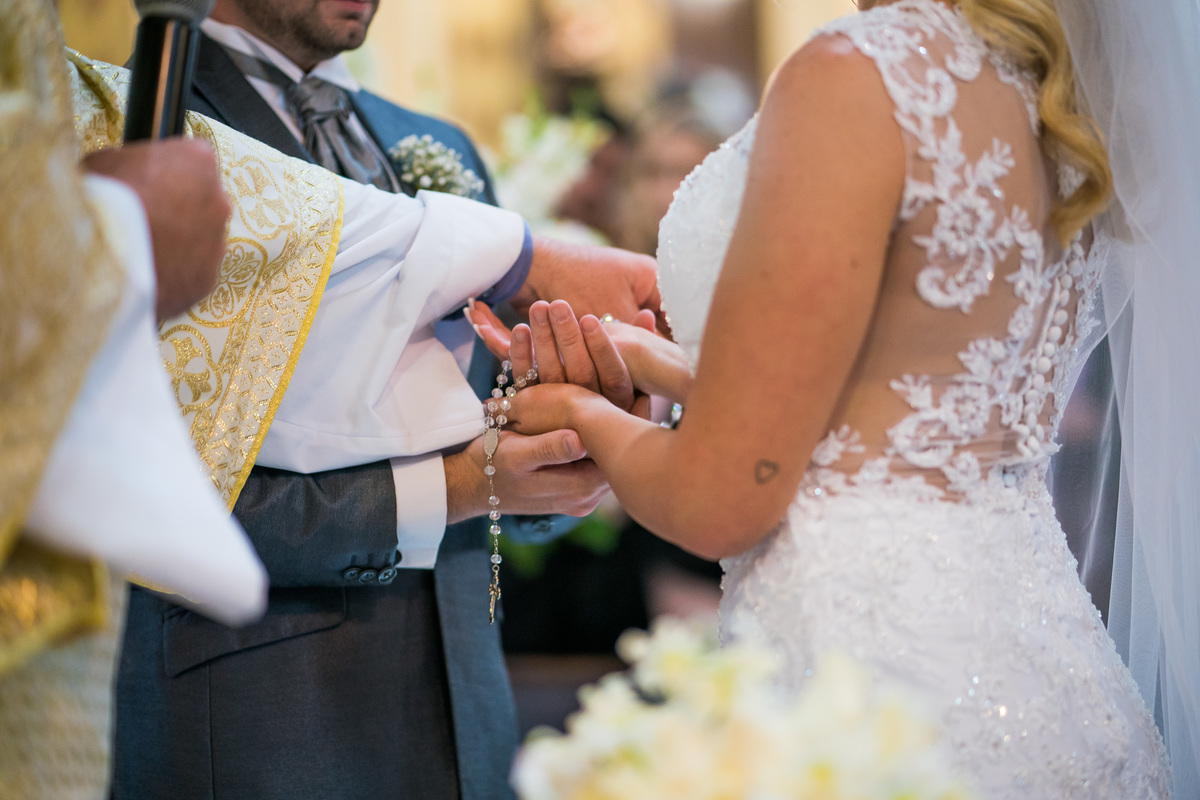 Casamento lindo da Ana Maria e Ricardo, na igreja Matriz, fotografado pelo fotógrafo de casamentos em Campo Largo e Curitiba, Michel Druziki. Padre abençoando as alianças com rosário entrelaçado nas mãos dos noivos
