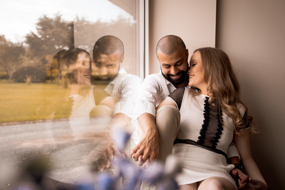 O fotógrafo de casamentos em Campo Largo e Curitiba, Michel Druziki fotografou o casal Daniela e Paulo em uma tarde ensolarada no Rancho P&R, em São Luiz do Purunã. Casal sentado na janela sorrindo.