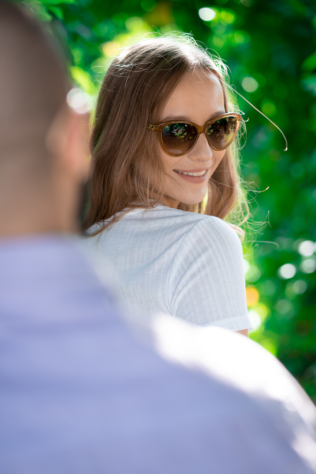 O fotógrafo de casamentos em Campo Largo e Curitiba, Michel Druziki fotografou o casal Daniela e Paulo em uma tarde ensolarada no Rancho P&R, em São Luiz do Purunã. Noiva de óculos de sol olhando para o noivo e sorrindo.