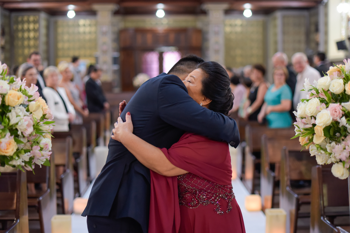 Casamento fotografado pelo fotógrafo Michel Druziki. Cerimônia de casamento dos noivos Denise e Marcelo foi realizada na igreja Matriz de Campo Largo. Mãe do noivo dando abraço no filho no altar da igreja.