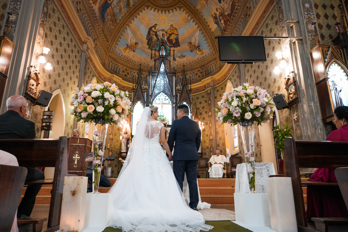 Casamento fotografado pelo fotógrafo Michel Druziki. Cerimônia de casamento dos noivos Denise e Marcelo foi realizada na igreja Matriz de Campo Largo. Noivos de mãos dadas no altar durante a cerimônia 