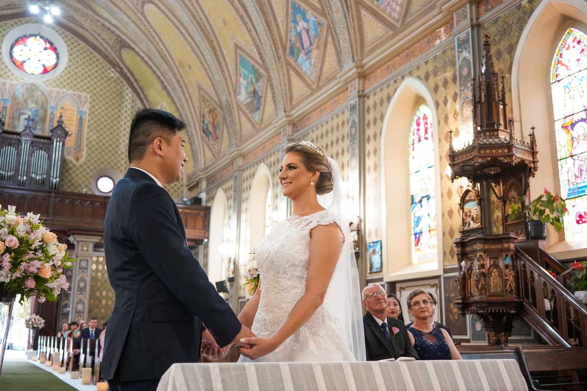Casamento fotografado pelo fotógrafo Michel Druziki. Cerimônia de casamento dos noivos Denise e Marcelo foi realizada na igreja Matriz de Campo Largo. Noivos de mãos dadas dentro da igreja