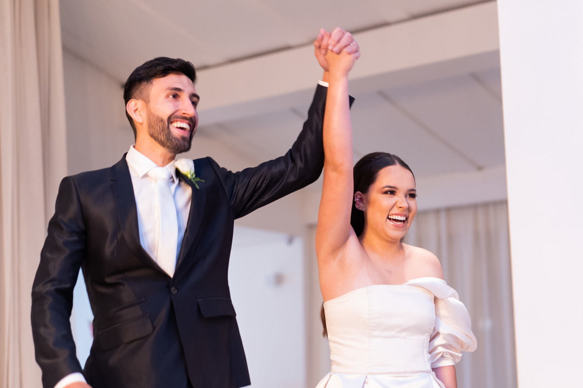 Curitiba Rebeca e Vinicius no Magiiore Barigui fotografado pelo fotógrafo de casamento Michel Druziki. Noivos sorrindo ao entrar na festa de mãos dadas