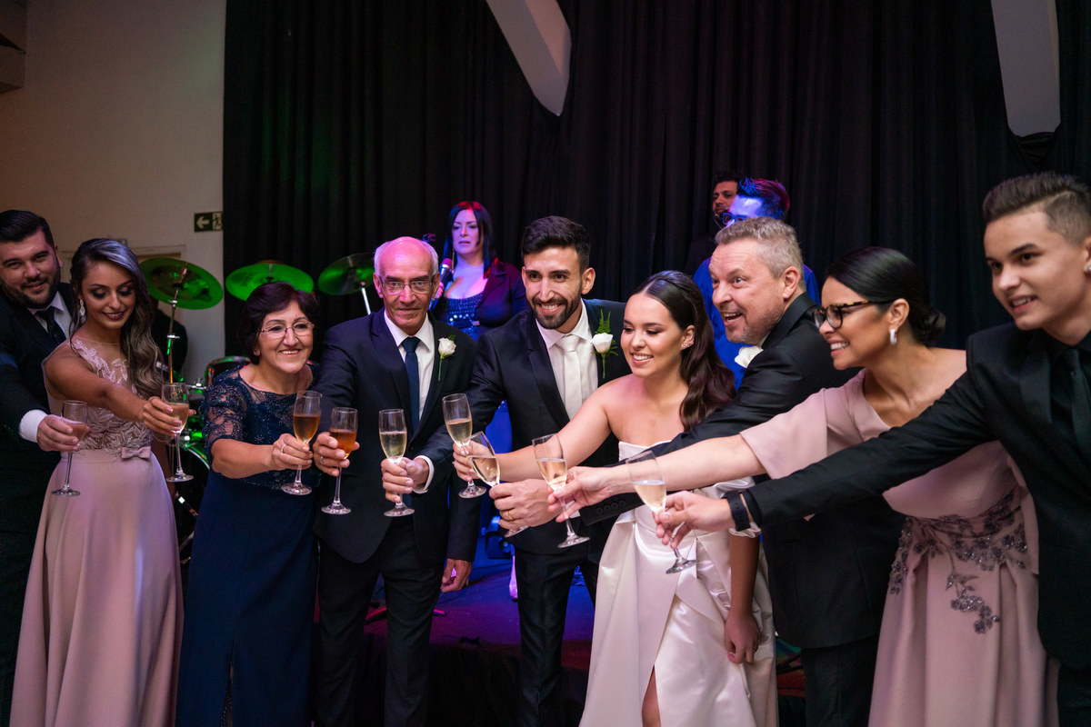 Curitiba Rebeca e Vinicius no Magiiore Barigui fotografado pelo fotógrafo de casamento Michel Druziki. Noivos sorrindo e brindando com os pais e convidados