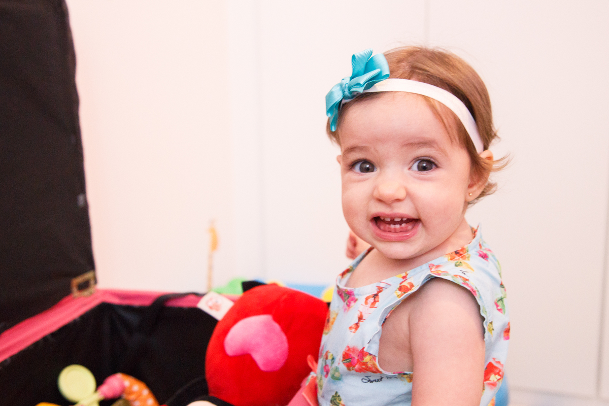 Bebê de um ano sentada em frente ao seu baú de brinquedos