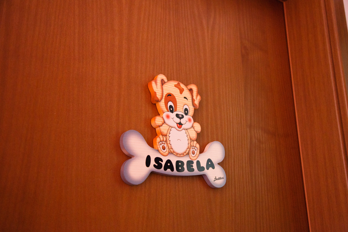 Enfeite de porta do quarto da bebê, com um cachorrinho e o nome dela escrito em um ossinho.
