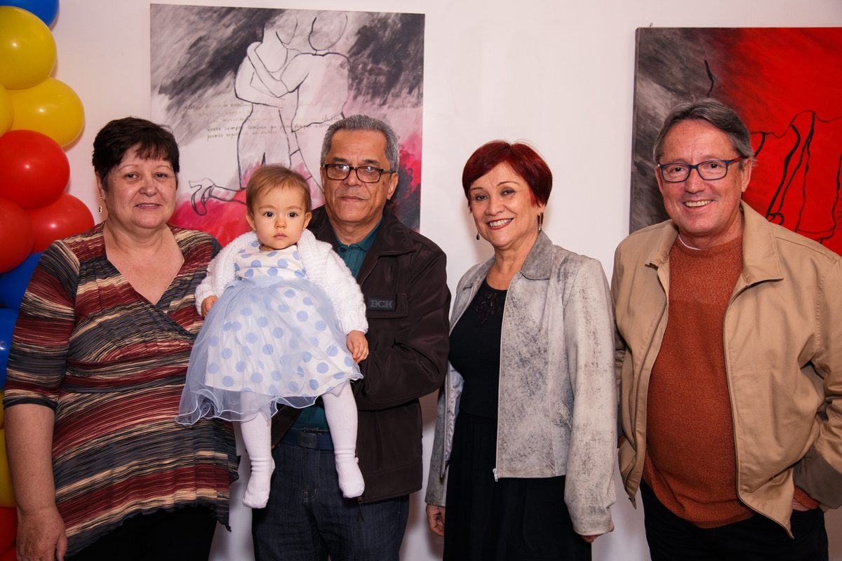 Avós e avôs maternos e paternos com a neta no colo posando apra foto em aniversário de 1 ano da bebê.