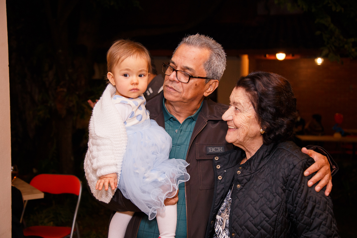 Bisavó, avô e sua netinha posando para foto no aniversário de 1 ano da bebê.