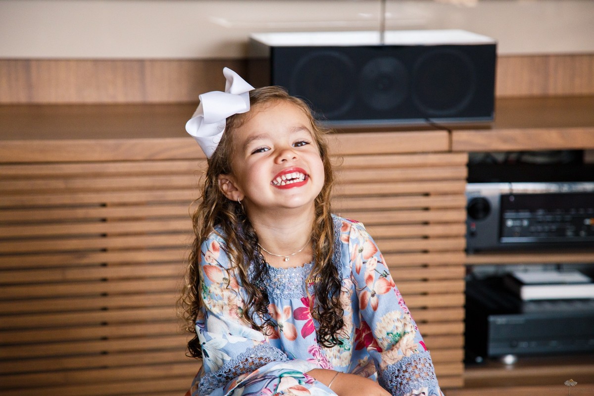 Criança posando para foto, olhando para câmera e gargalhando.