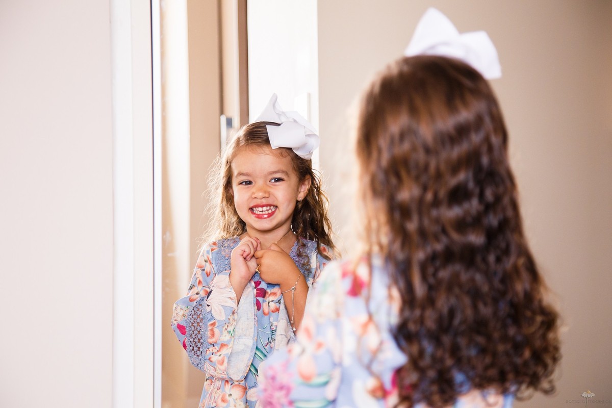 Criança sorrindo para o espelho durante ensaio fotográfico infantil.