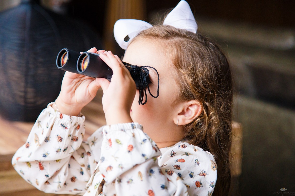 Criança olhando através de um binóculo tamanho infantil.