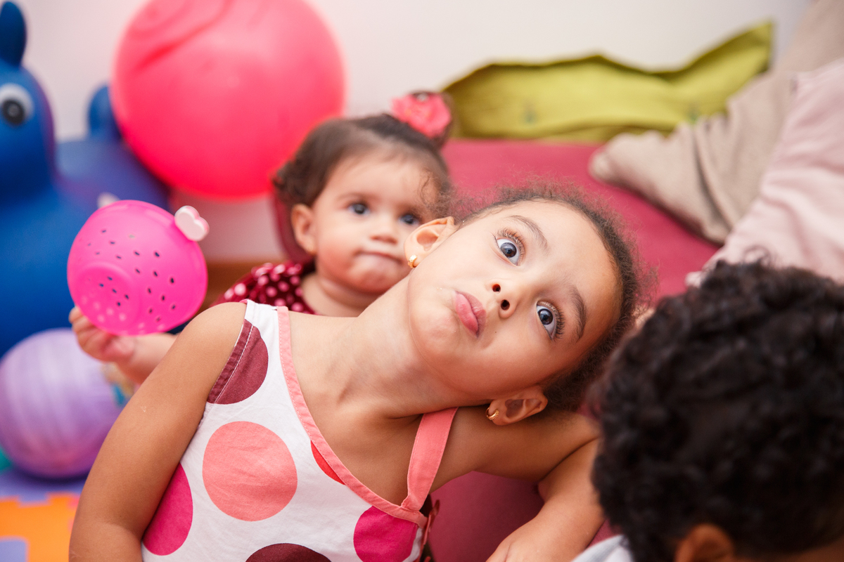 Criança brincando, fazendo careta, durante festa de aniversário de 1 ano de sua irmã.