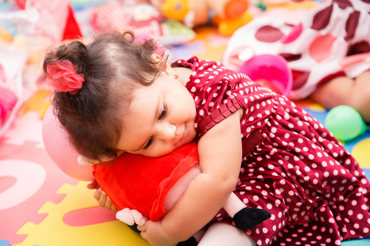 Bebê de 1 ano em seu aniversário abraçando a Pepa Pig no quarto de brinquedos.