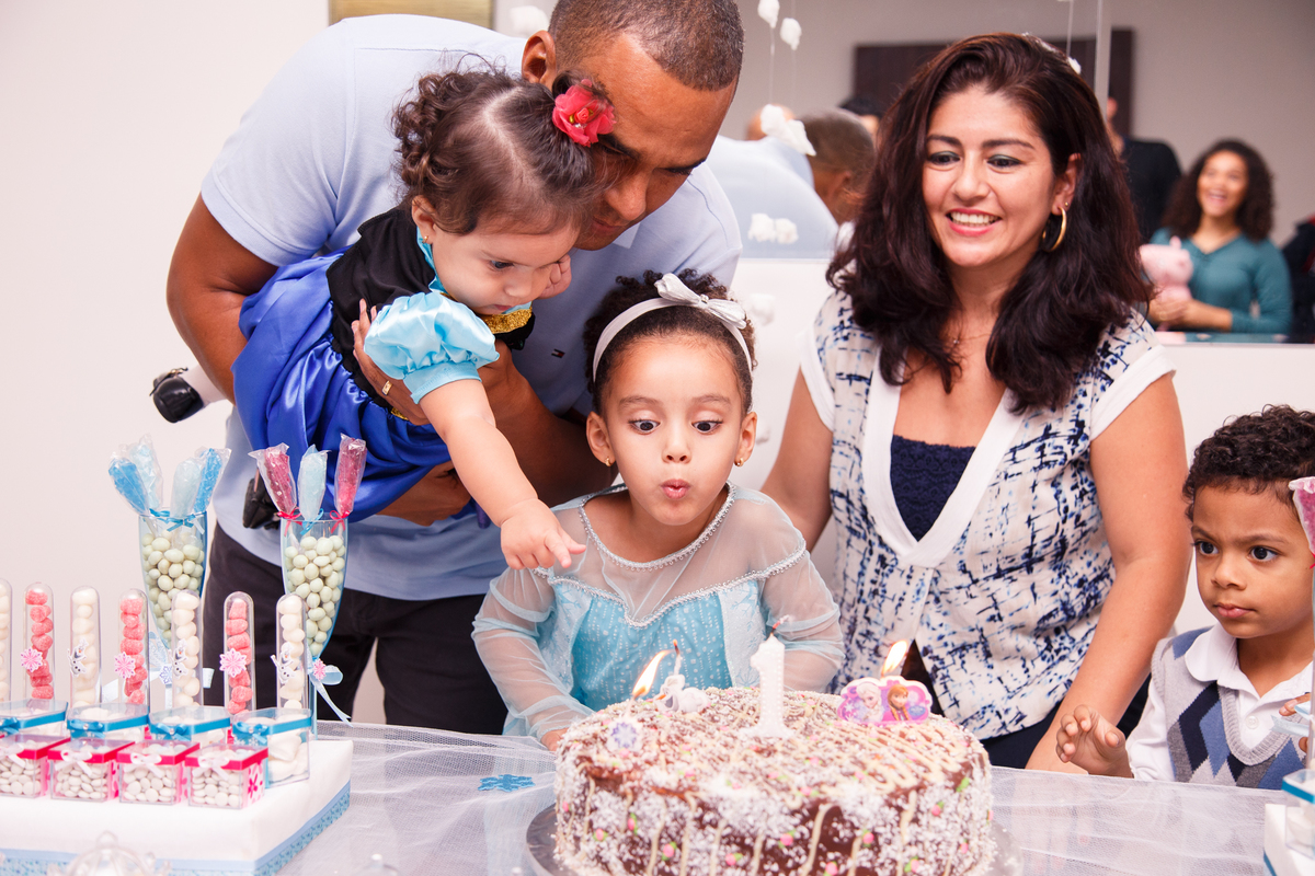 Crianças soprando a velinha de aniversário após o parabéns em aniversário de 1 ano.