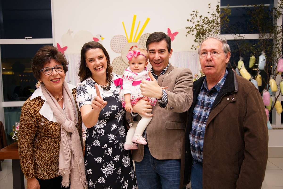 Pais com seu bebê no colo posando junto com os avôs paternos.