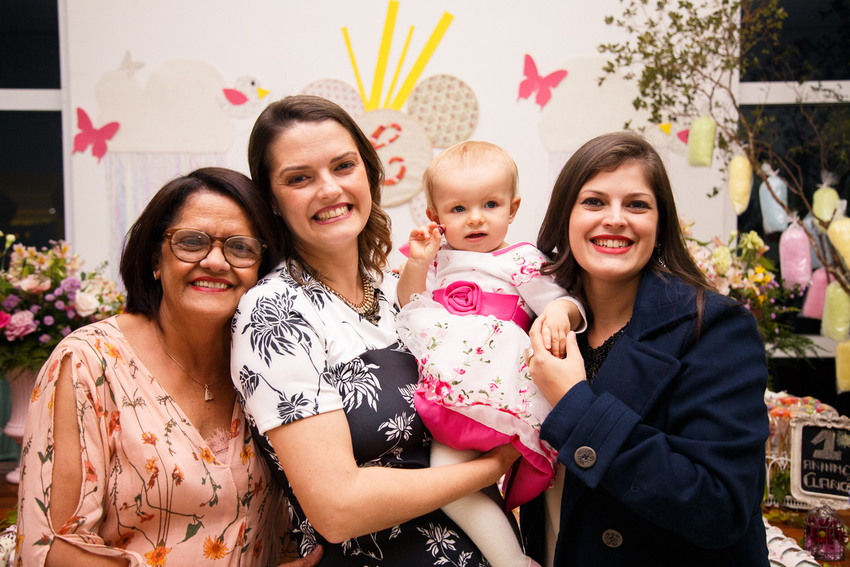 Mãe com sua bebê no colo posando para foto junto com sua mãe e irmã.