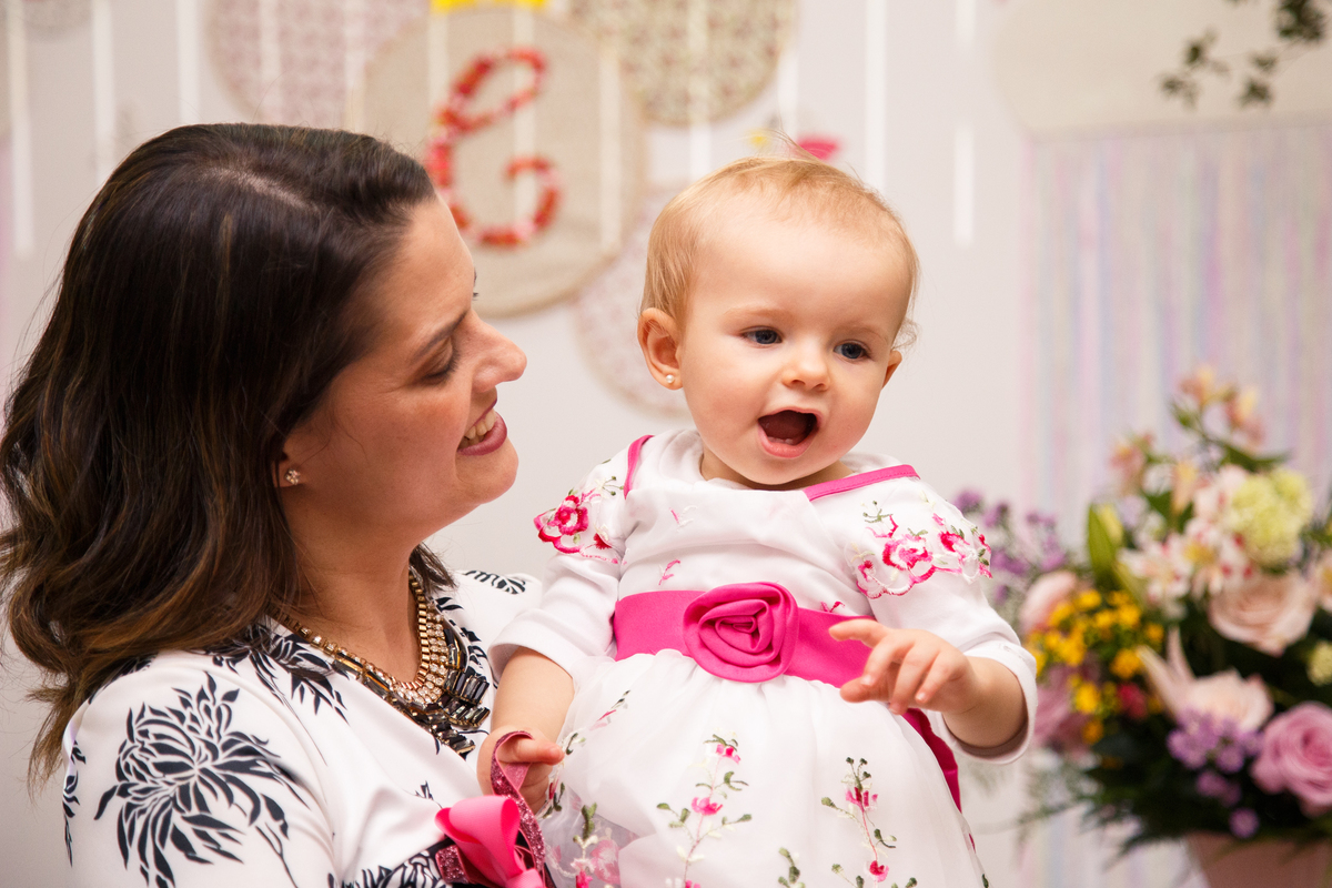 Mãe com sua filha no colo, as duas brincando e rindo.
