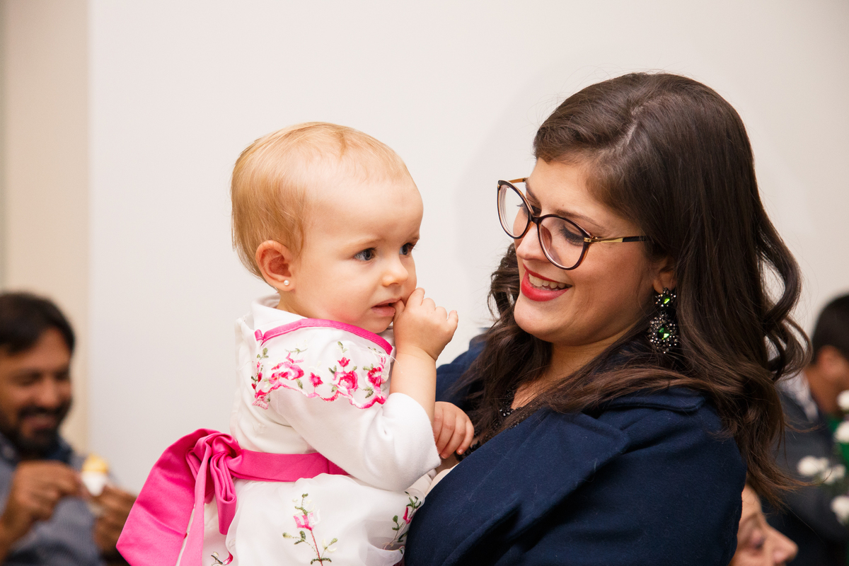 Tia com a bebê aniversariante no colo sorrindo.