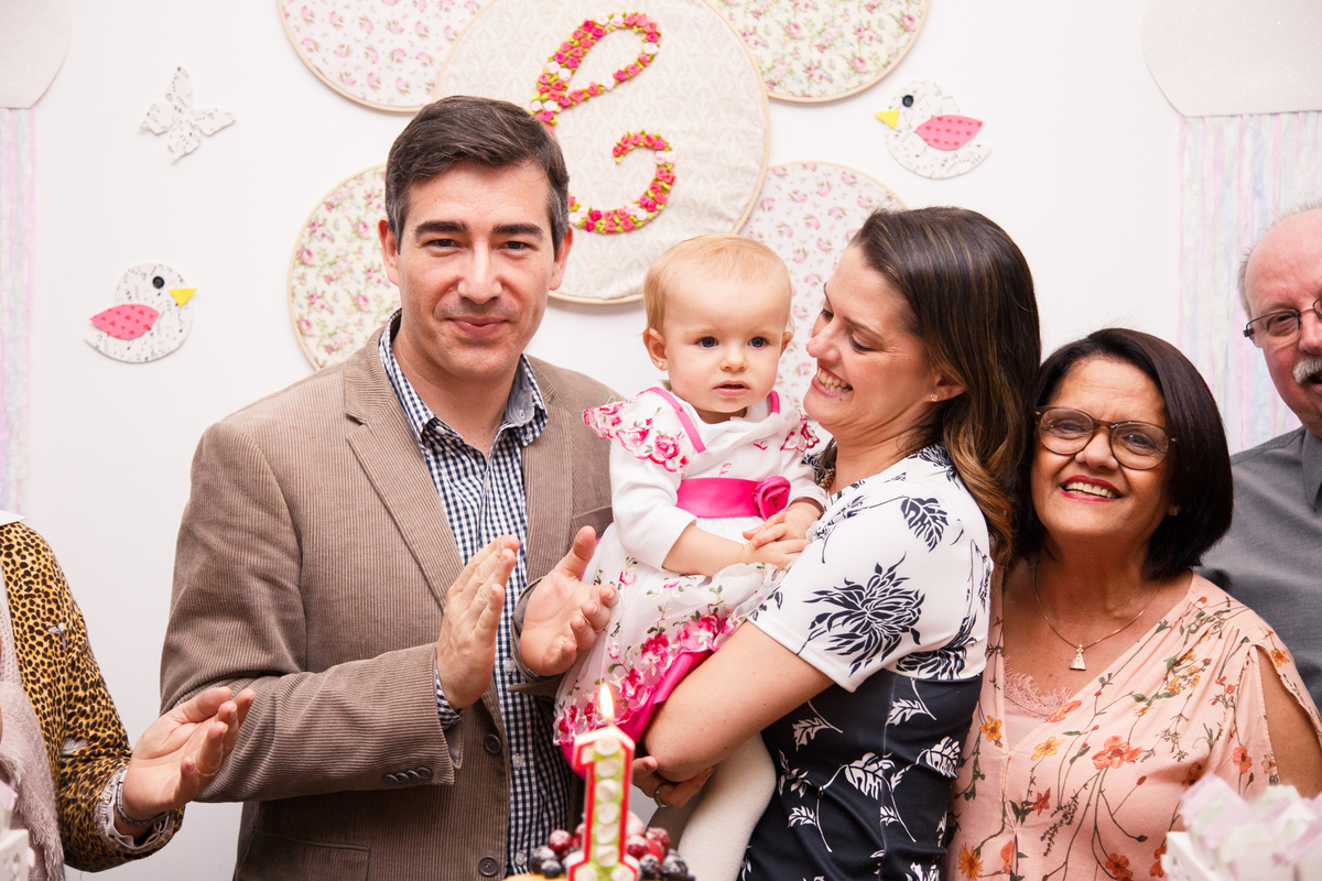 Pais atrás da mesa do bolo cantando parabéns durante aniversário infantil.