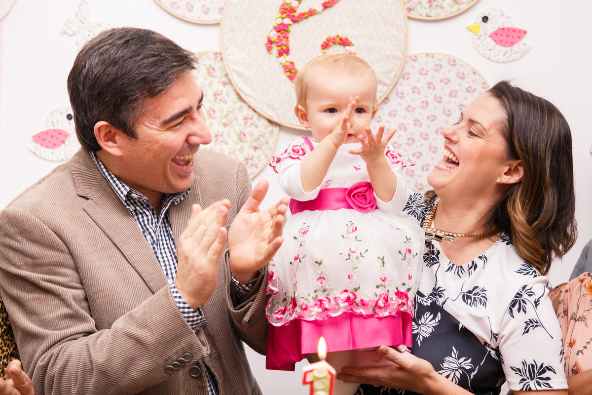 Bebê de um ano batendo palminhas durante o parabéns em sua festa de aniversário.