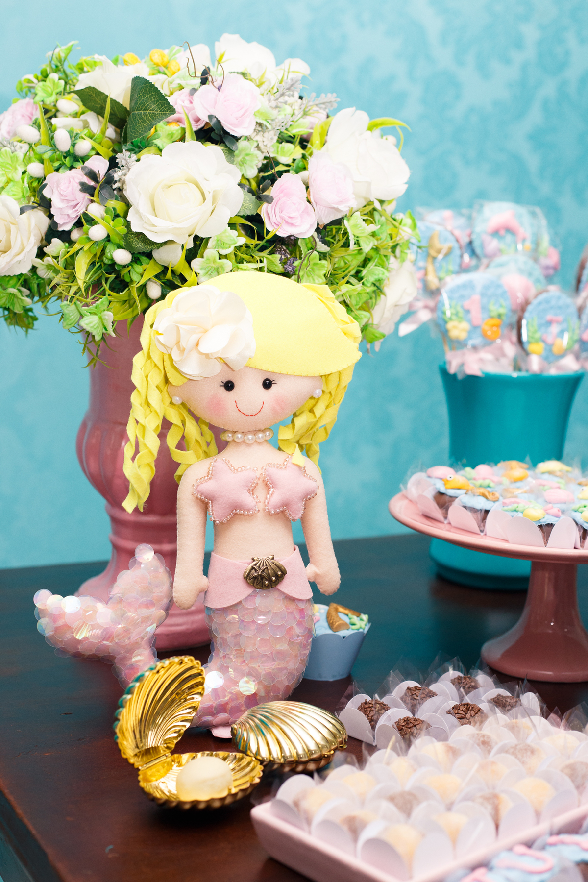 Detalhe na decoração da mesa do bolo com uma sereia, no tema sereismo.