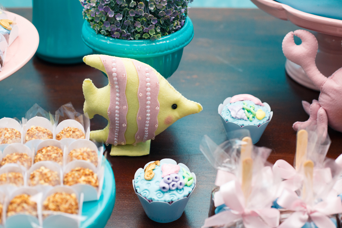 Detalhe da mesa do bolo de aniversário infantil, com decoração de peixes e outros animais marinhos no tema fundo do mar.
