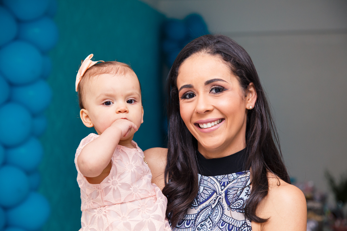 Bebê aniversariante no colo da sua mãe em sua festa de 1 ano.