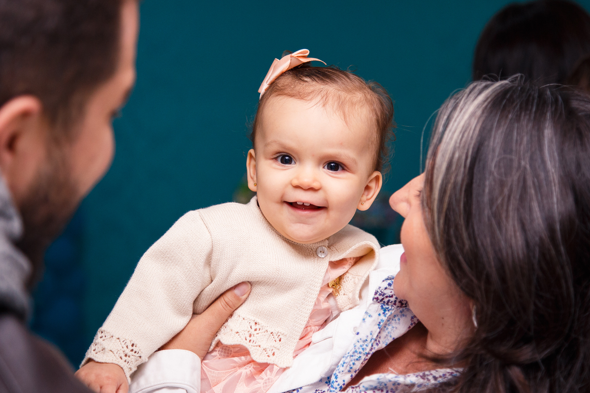 Bebê no colo sorrindo, olhando para a foto.