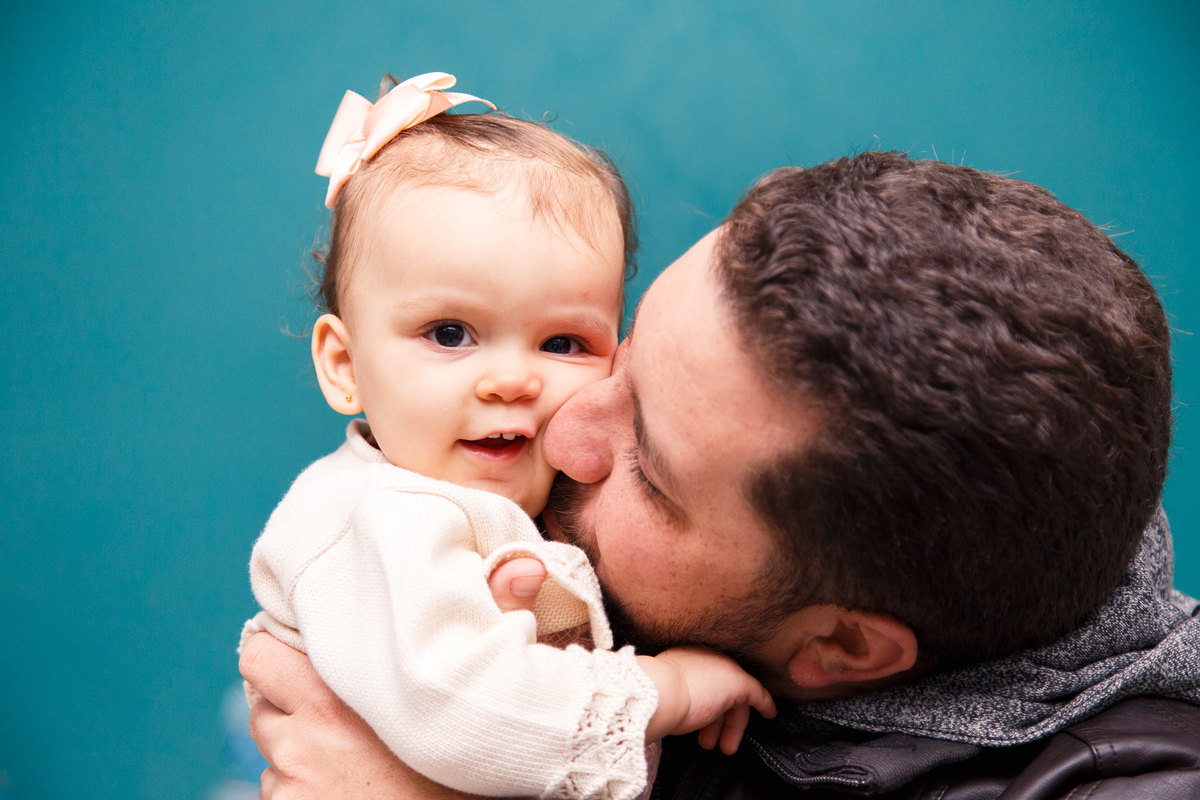 Bebê sorrindo ganhando um beijo de seu padrinho.
