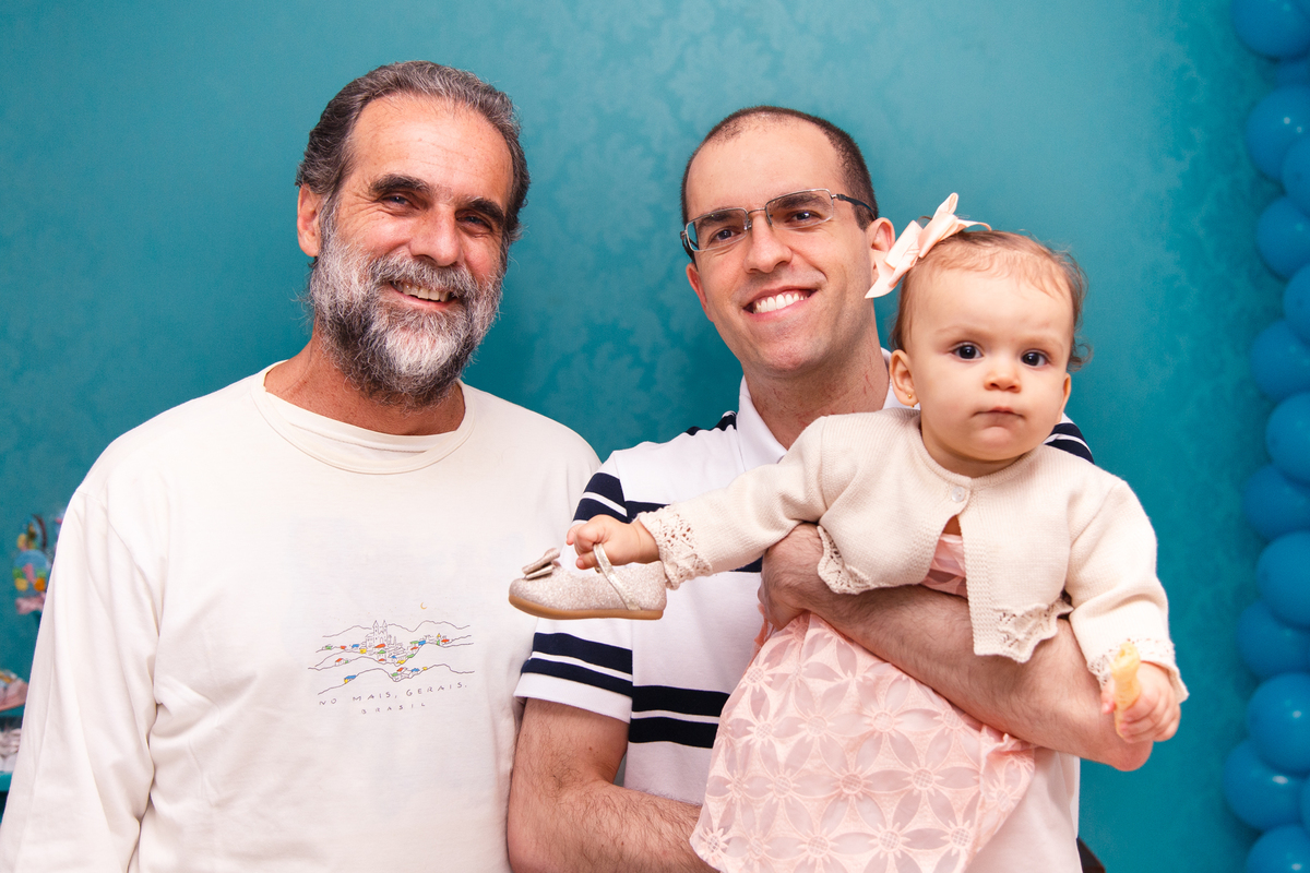 Bebê no colo de seu pai posando para foto junto com seu avô.