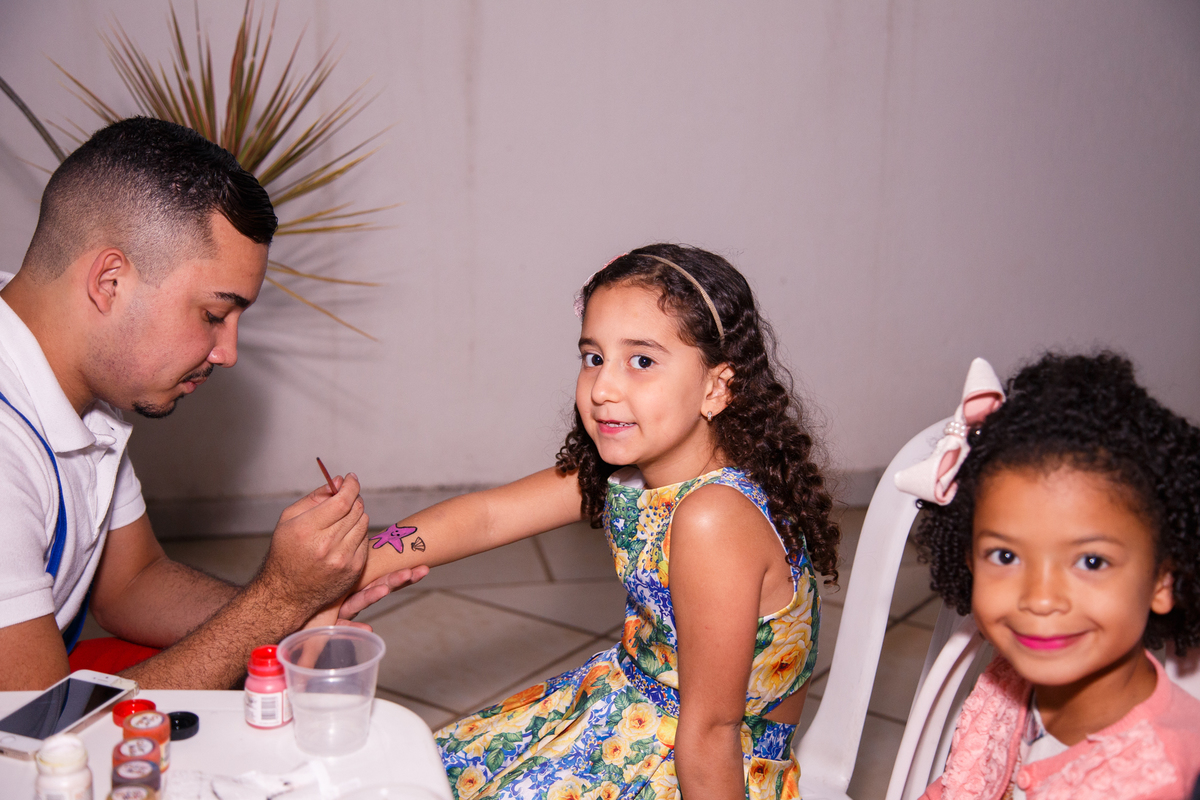 Animador da festa pintando o braço das crianças.