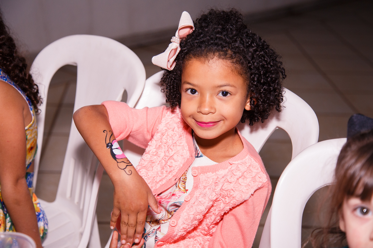 Criança mostrando para a foto a pintura que acabou de fazer no braço.