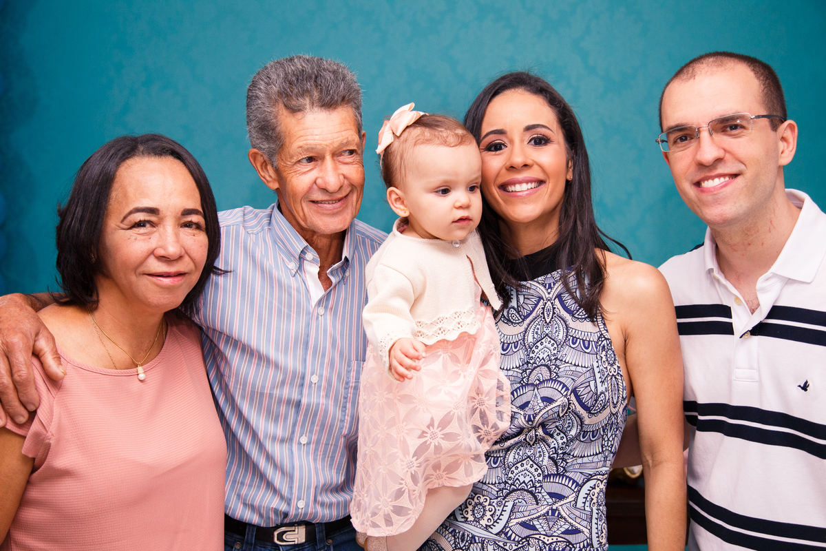 Pais com sua bebê no colo posando para foto com avós maternos.