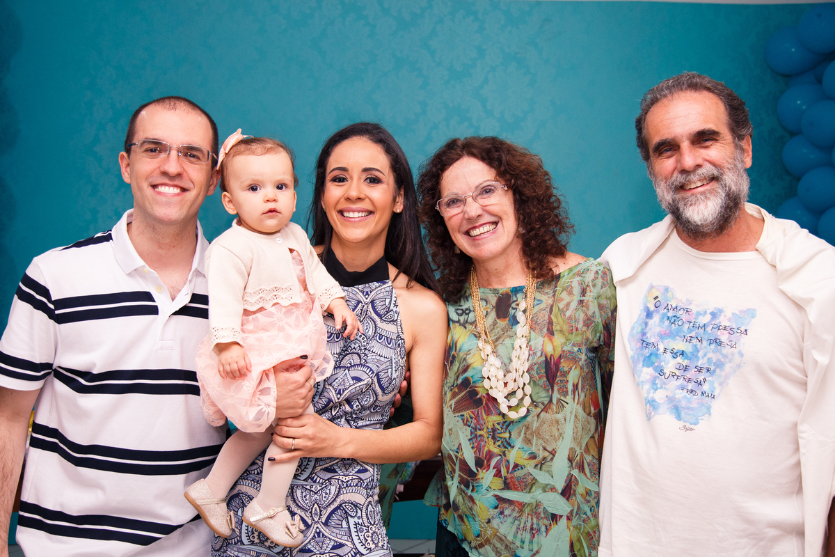 Pais com sua bebê no colo posando para foto com os avós paternos.