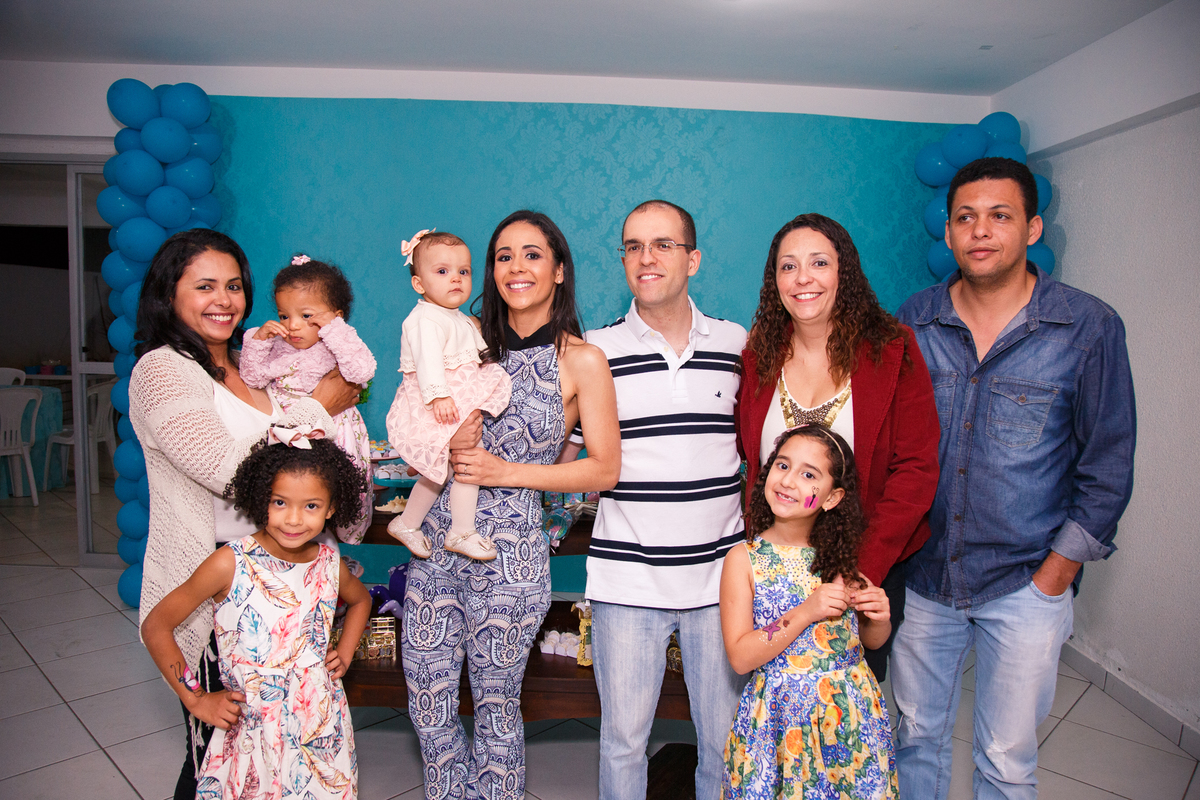 Pais com sua bebê posando para foto junto com todos os tios maternos.