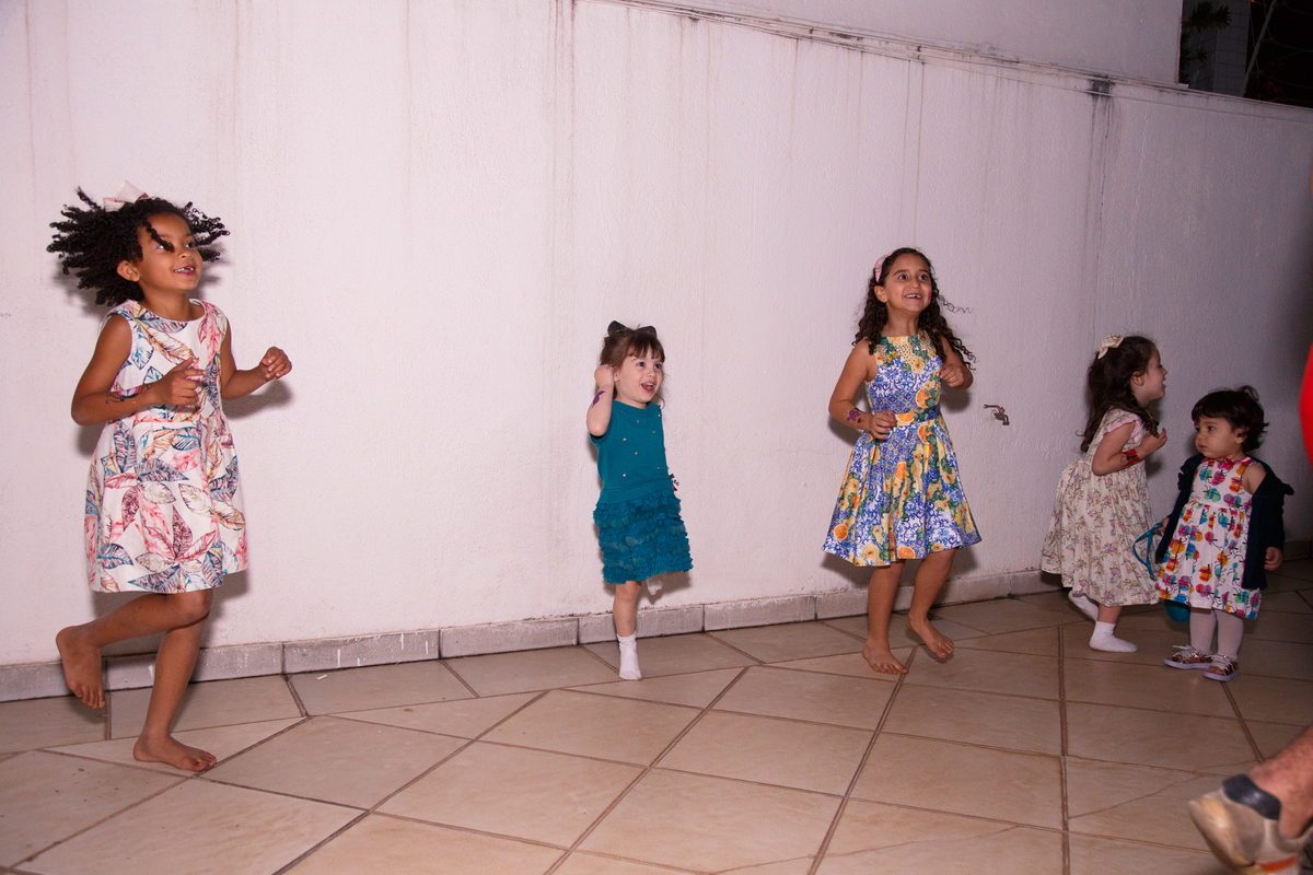 Crianças pulando e brincando na área externa durante aniversário infantil.