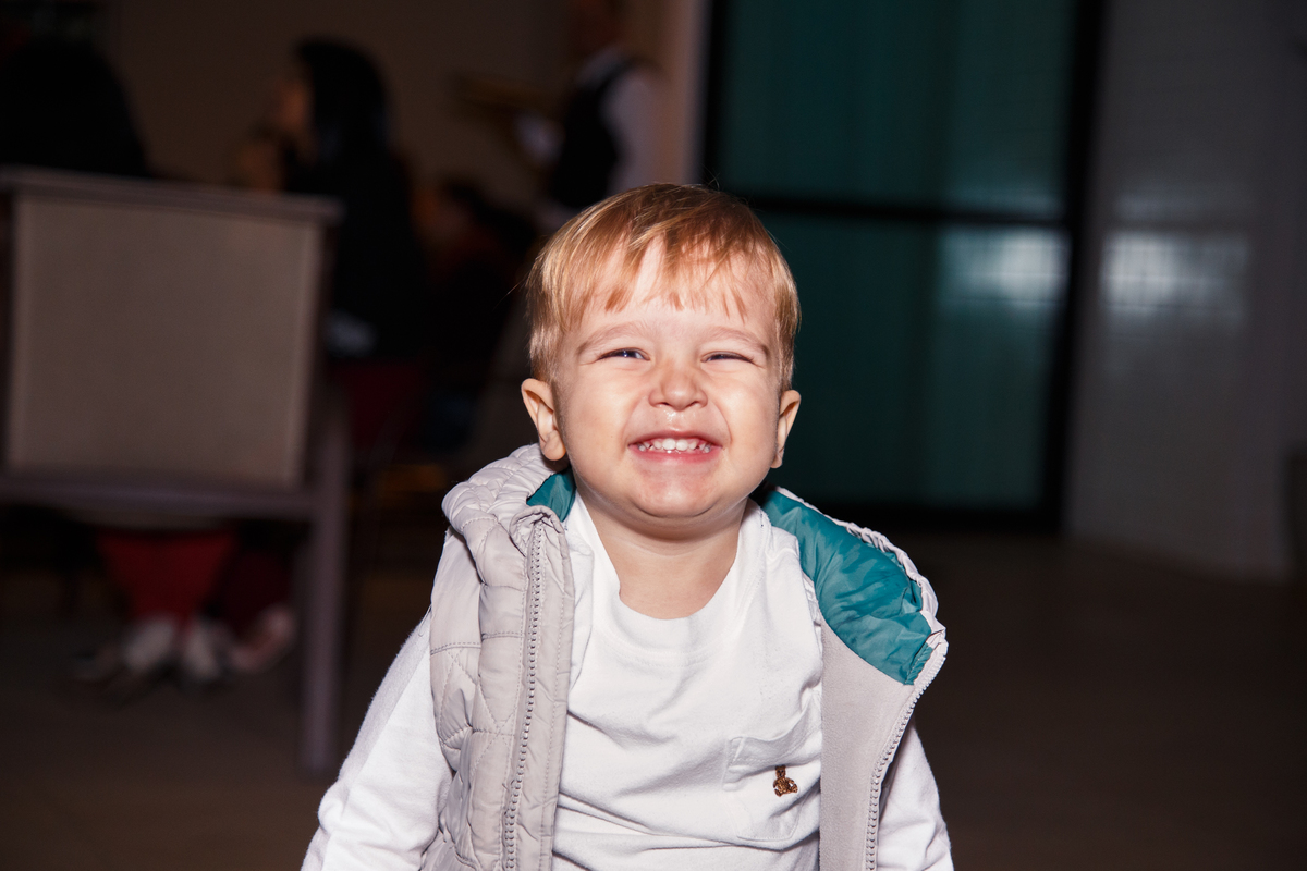 Criança olhando para a câmera e sorrindo durante festa de aniversário infantil.