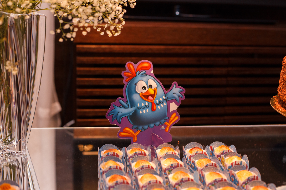 Detalhe de doces na mesa do bolo em aniversário infantil no tema galinha pintadinha.