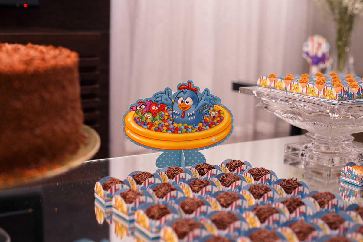 Detalhe de doces na mesa do bolo em aniversário infantil no tema galinha pintadinha.