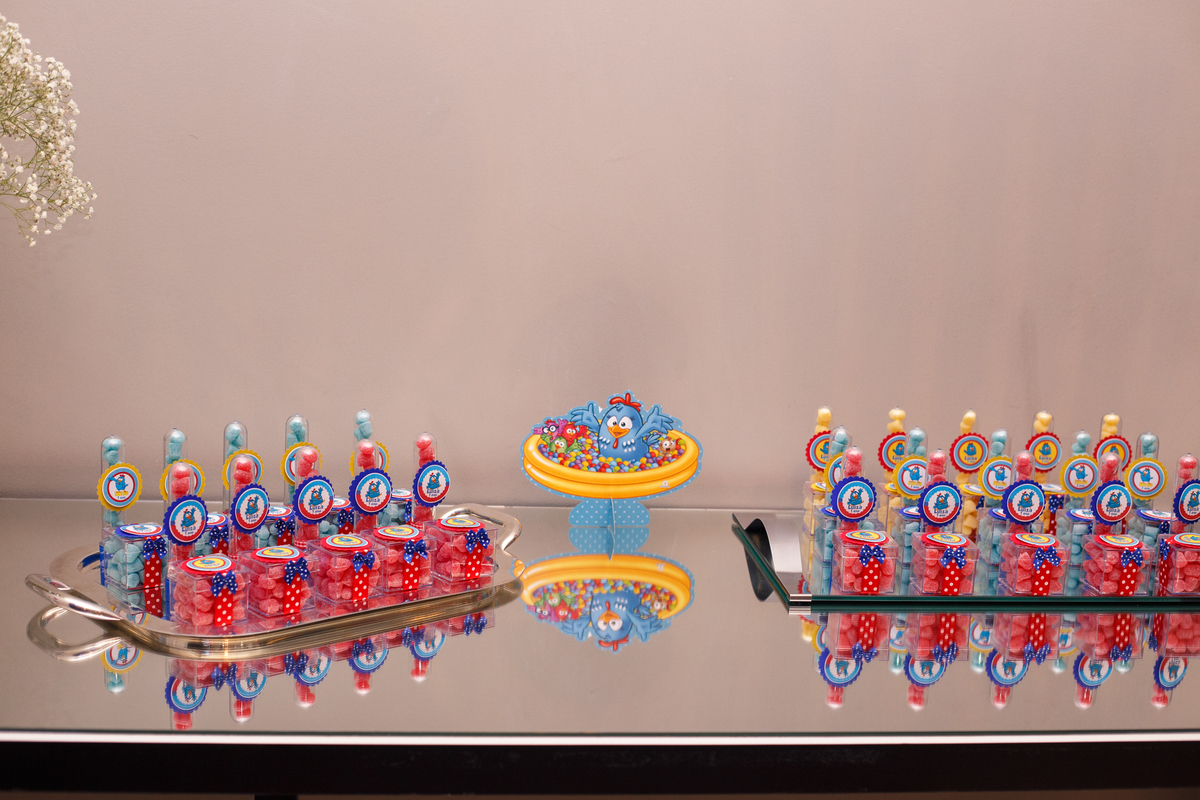 Detalhe da mesa de doces e balas em aniversário infantil no tema galinha pintadinha.