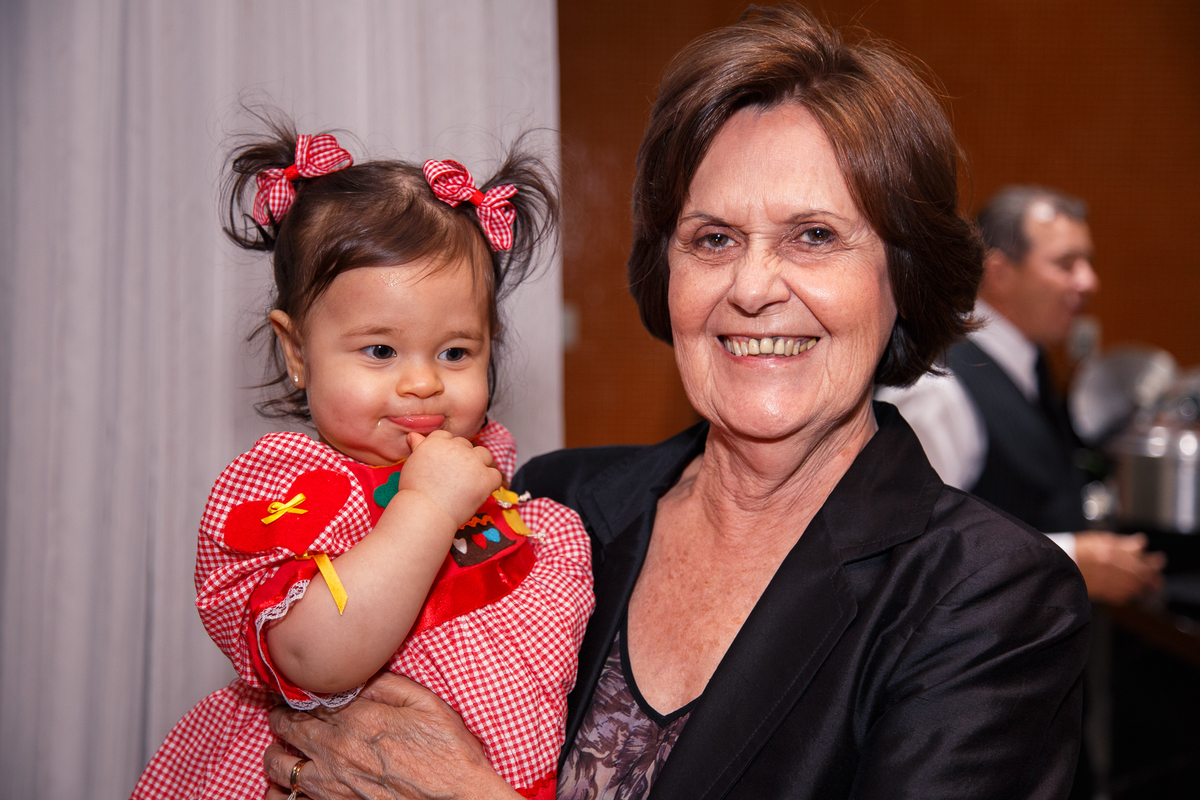 Bebê aniversariante no colo da avó posando para foto.