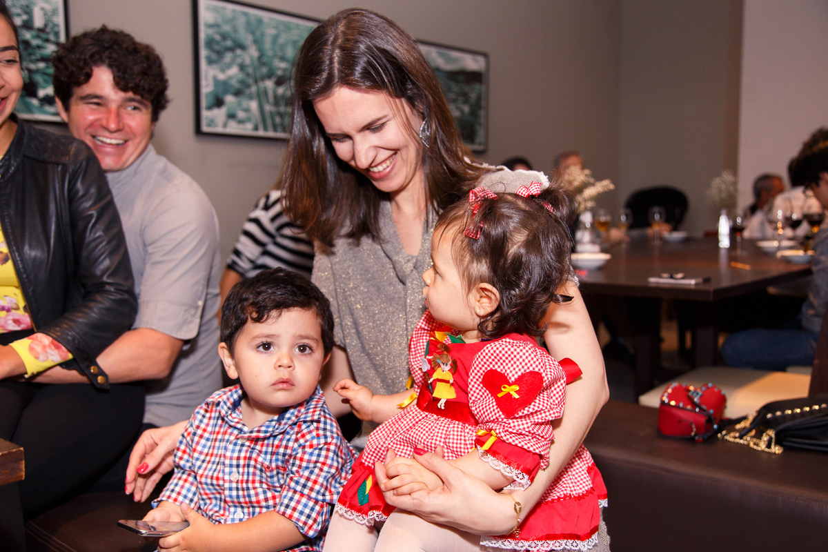 Mãe com sua bebê e outra criança no colo sorrindo.