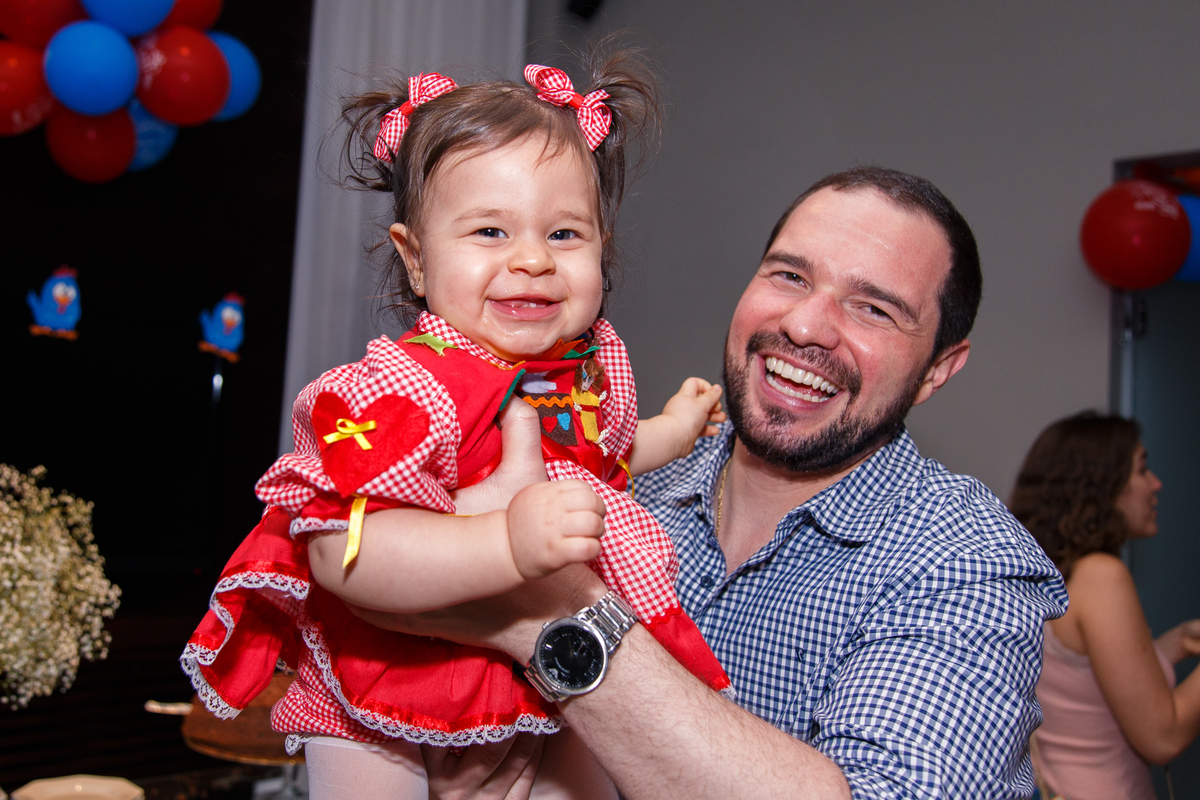 Pai brincando de aviãozinho com a bebê que ri muito.