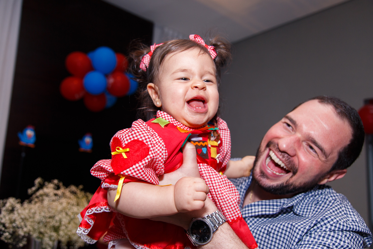 Pai se divertindo com a bebê, brincando de aviãozinho. A bebê dá gargalhada.