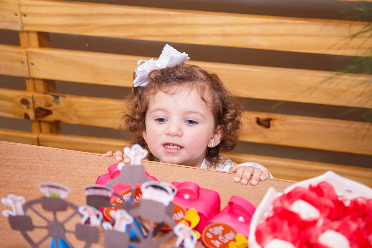 Vista de cima de uma criança tentando olhar em cima da mesa do bolo de sua festa de aniversário.