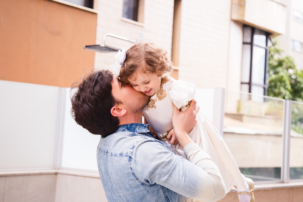 Criança sendo levantada por um tio e ganhando um beijo durante seu aniversário de 2 anos.