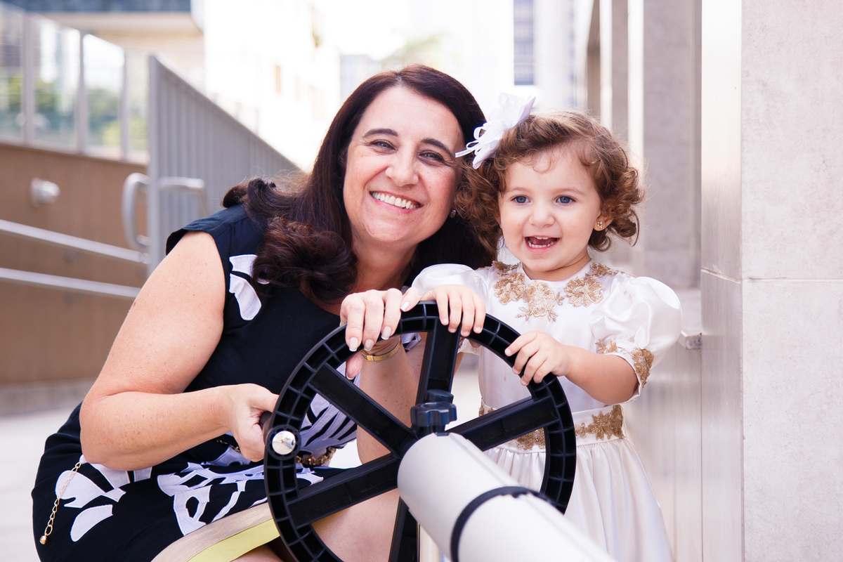 Criança e sua avó brincando com um volante, ambas sorrindo.