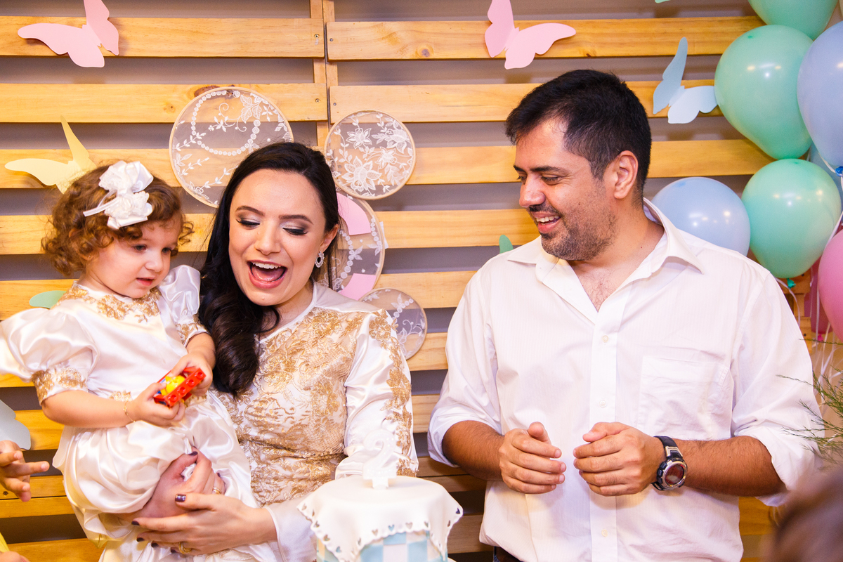 Criança e seus pais celebrando o parabéns de sua festa de aniversário.