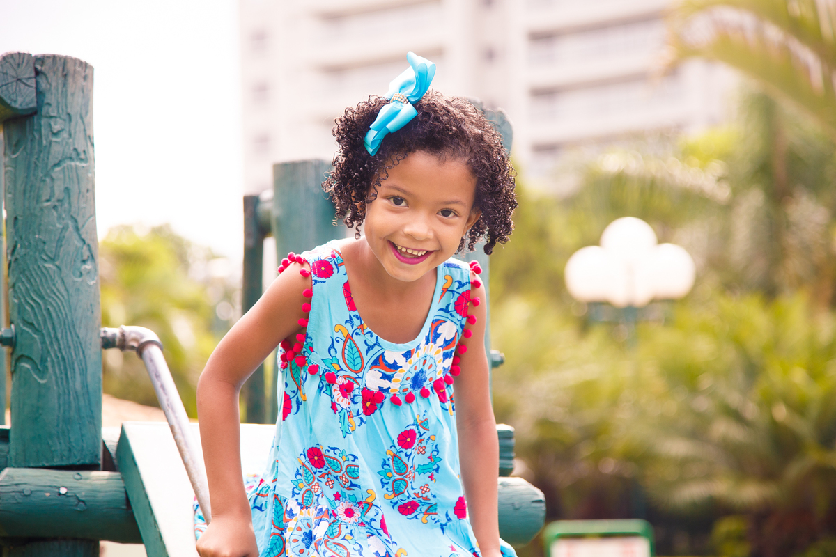 Criança sorrindo olhando para câmera e brincando no escorregador.